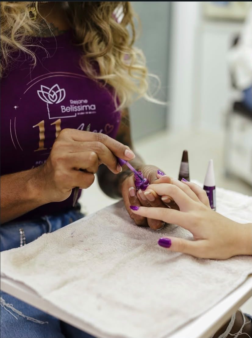 Profissional aplicando esmalte nas unhas de uma cliente